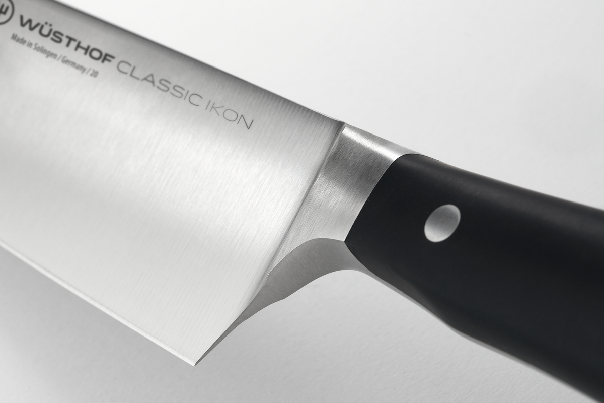 Close-up of the half bolster connecting the polished forged German steel blade to the black ergonomic handle in the Classic Ikon 2-Piece Cook's Set.
