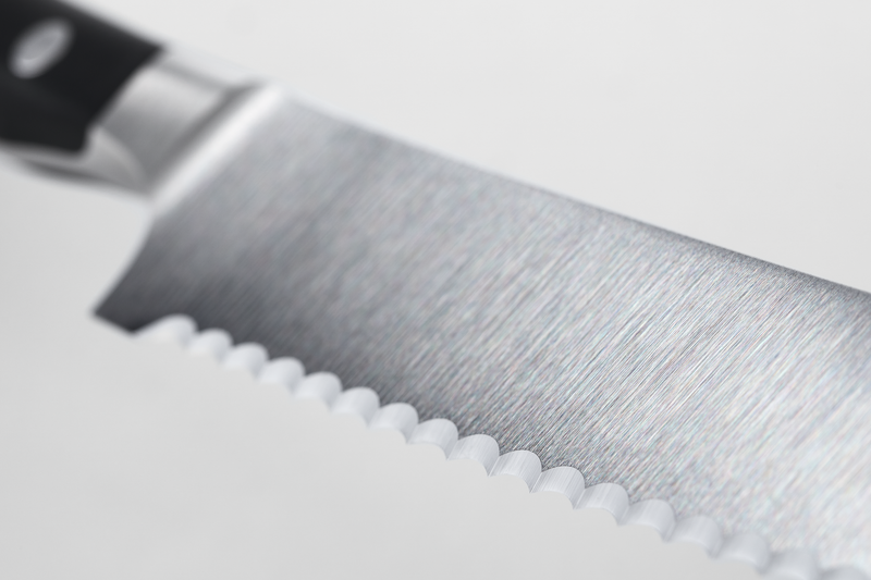Close-up of the serrated blade edge with brushed finish and triple-riveted black handle from the Classic Ikon 7-Piece Knife Block Set, featuring forged German steel.