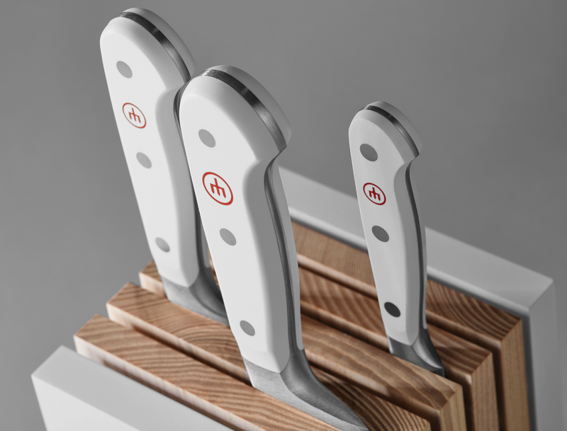 Classic Designer Knife Block showing ergonomic white handles with triple rivets on forged German stainless steel knives securely stored in a light wood block.