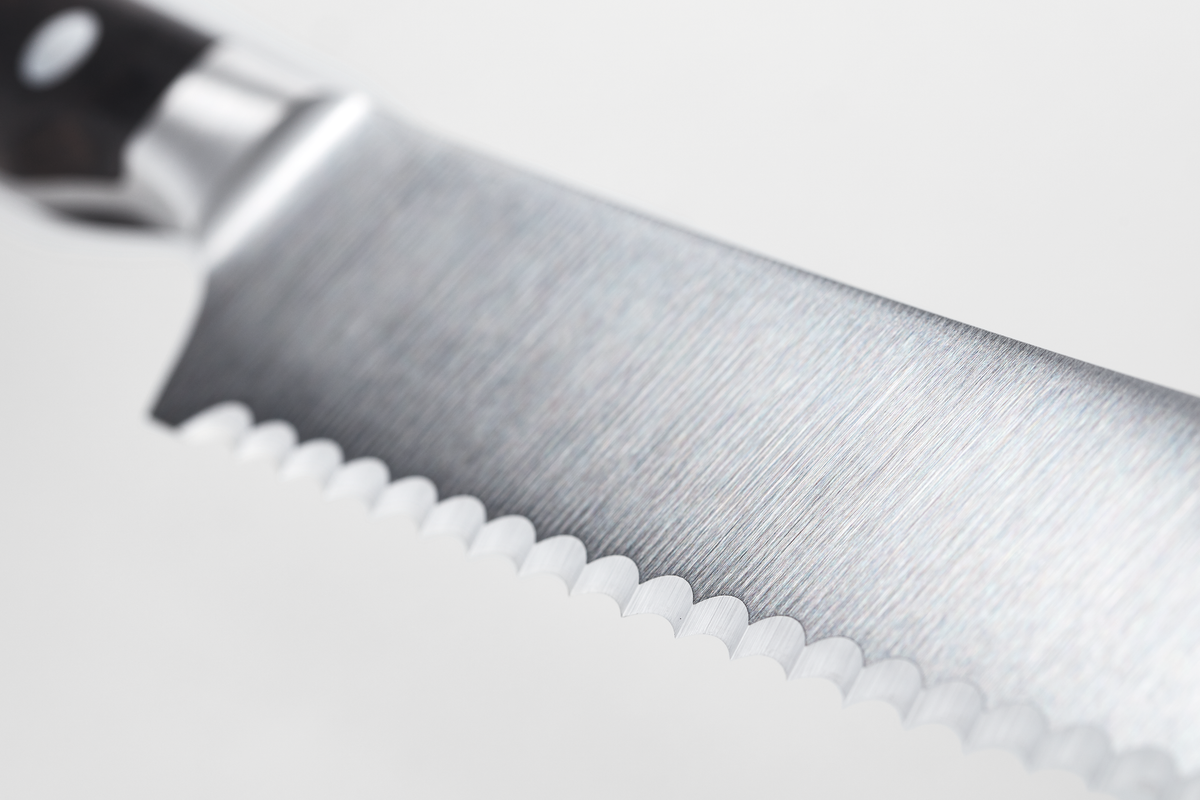 Ikon 8" Bread Knife with serrated forged stainless steel blade and dark wooden handle with three rivets, designed for precise slicing of bread.