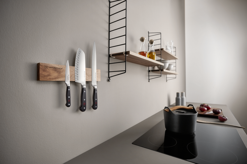 12" Wooden Magnetic Holder mounted on a kitchen wall holding three forged kitchen knives with black handles, showcasing natural wood and clean design.