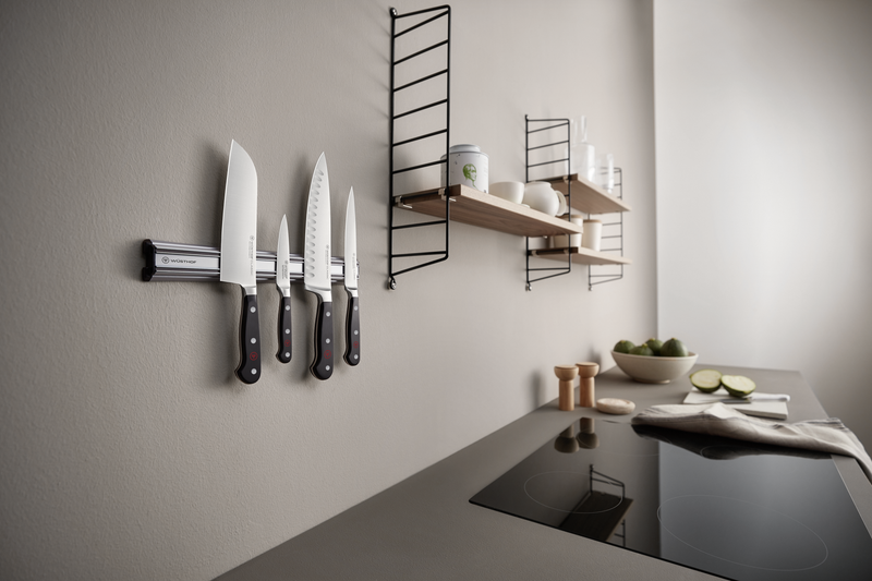 18" Magnetic Holder mounted on a kitchen wall securely holding four forged kitchen knives with a sleek, brushed steel finish.